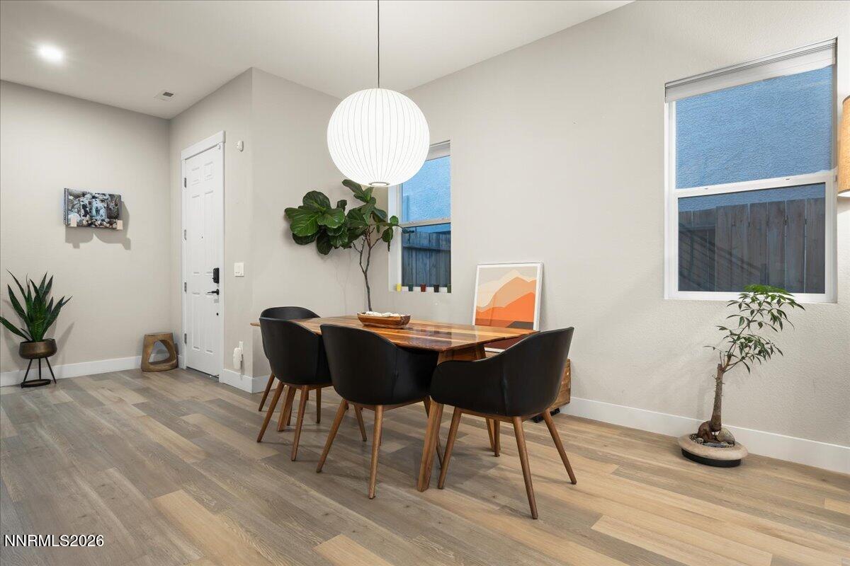 Dining room with a wood table, black chairs, round pendant light, and large windows.