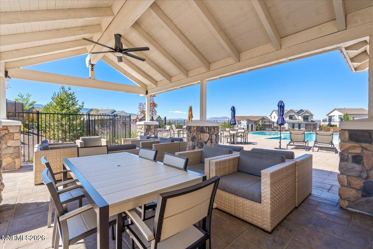 Covered community patio with wicker seating and dining table overlooking a swimming pool.