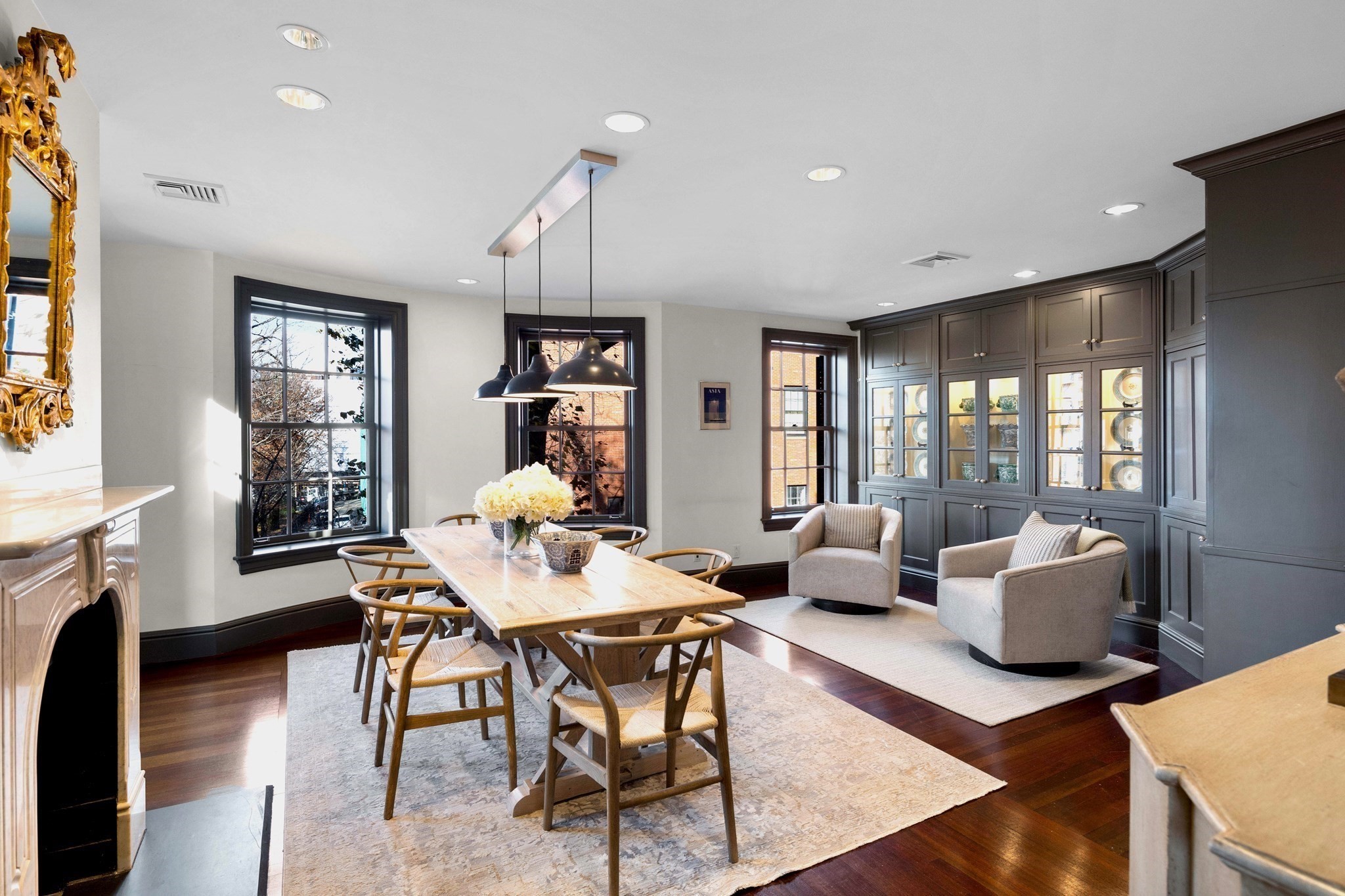 Dining room with a wooden table, dark built-in display cabinets, and a pair of upholstered armchairs.