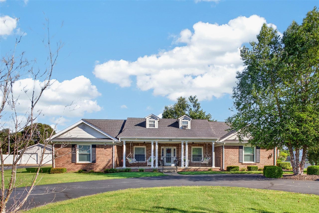 Brick home with a covered porch, two dormers, and a broad lawn.