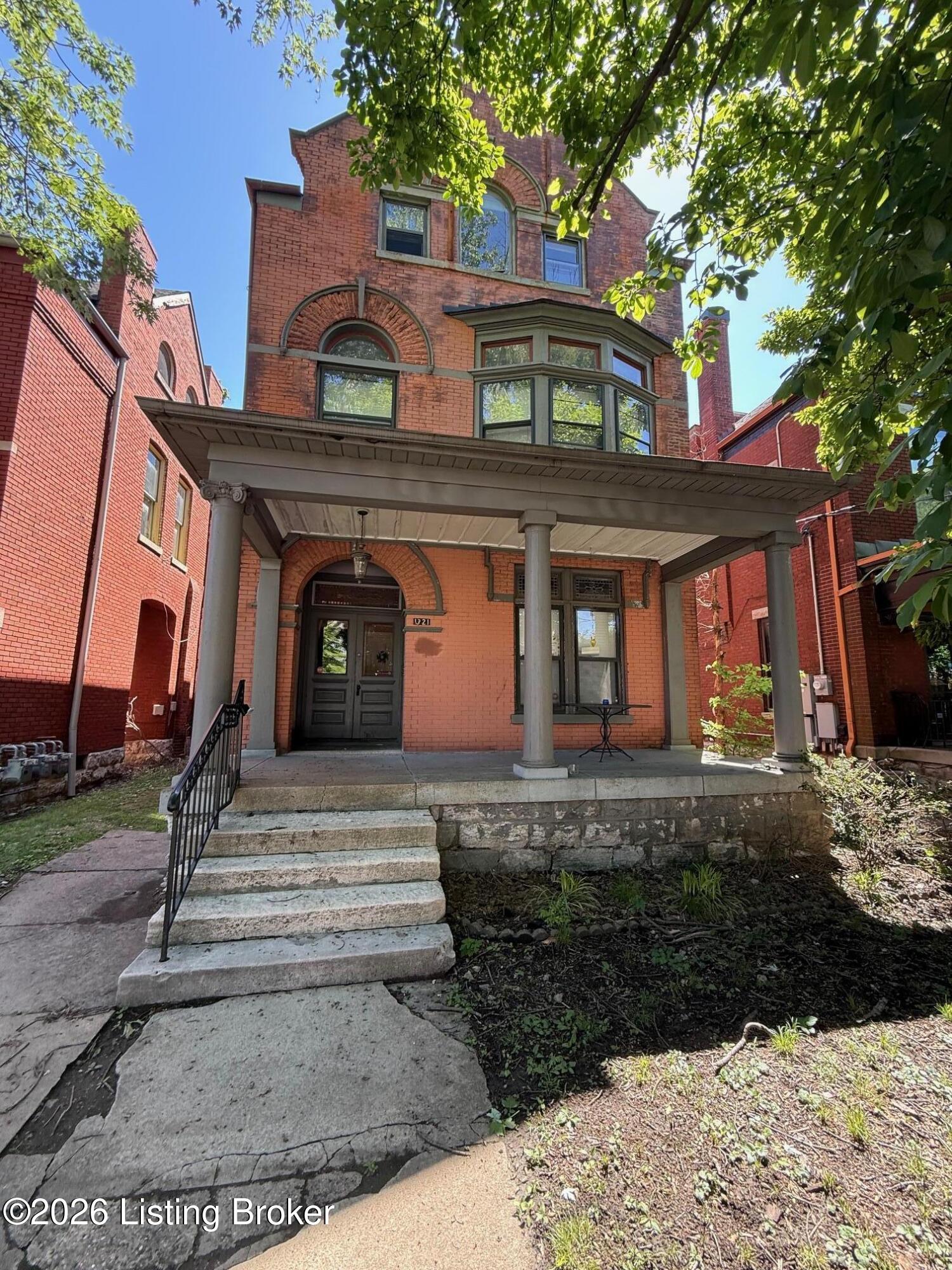 Historic red-brick home with arched windows, a columned porch, and stone steps.
