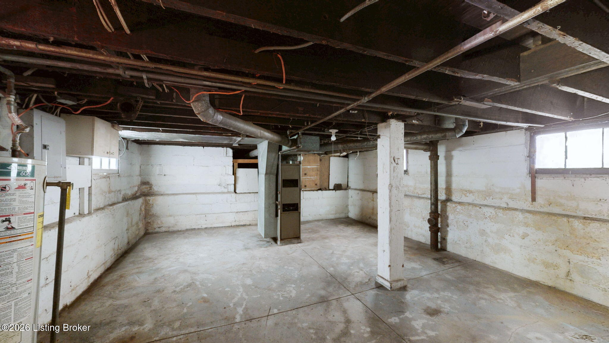 Unfinished basement with exposed joists and utility equipment, including a water heater and furnace.