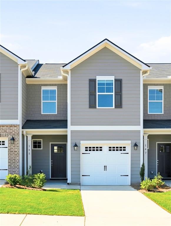 Gray two-story townhouse with blue shutters, white garage door, and front lawn.