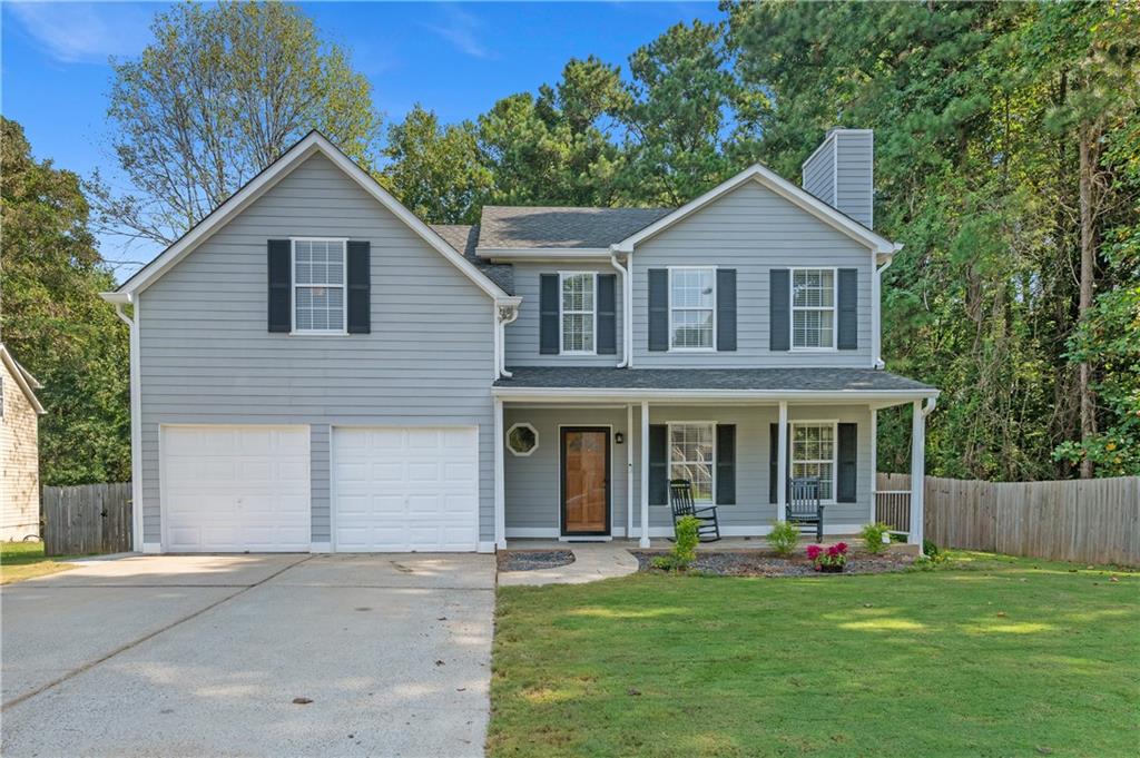 Gray two-story house with a covered porch, black shutters, and a two-car garage.
