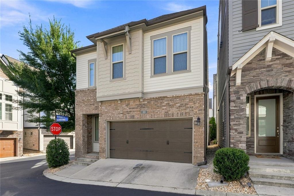 Two-story townhouse with a brick facade, attached garage, and landscaped driveway.