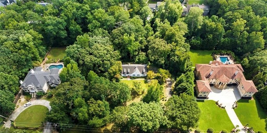 Aerial view of wooded Sandy Springs estates, including a large home with a circular driveway and swimming pool.
