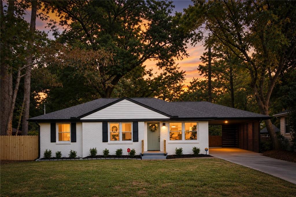 White brick ranch house with black shutters and a covered carport at dusk.