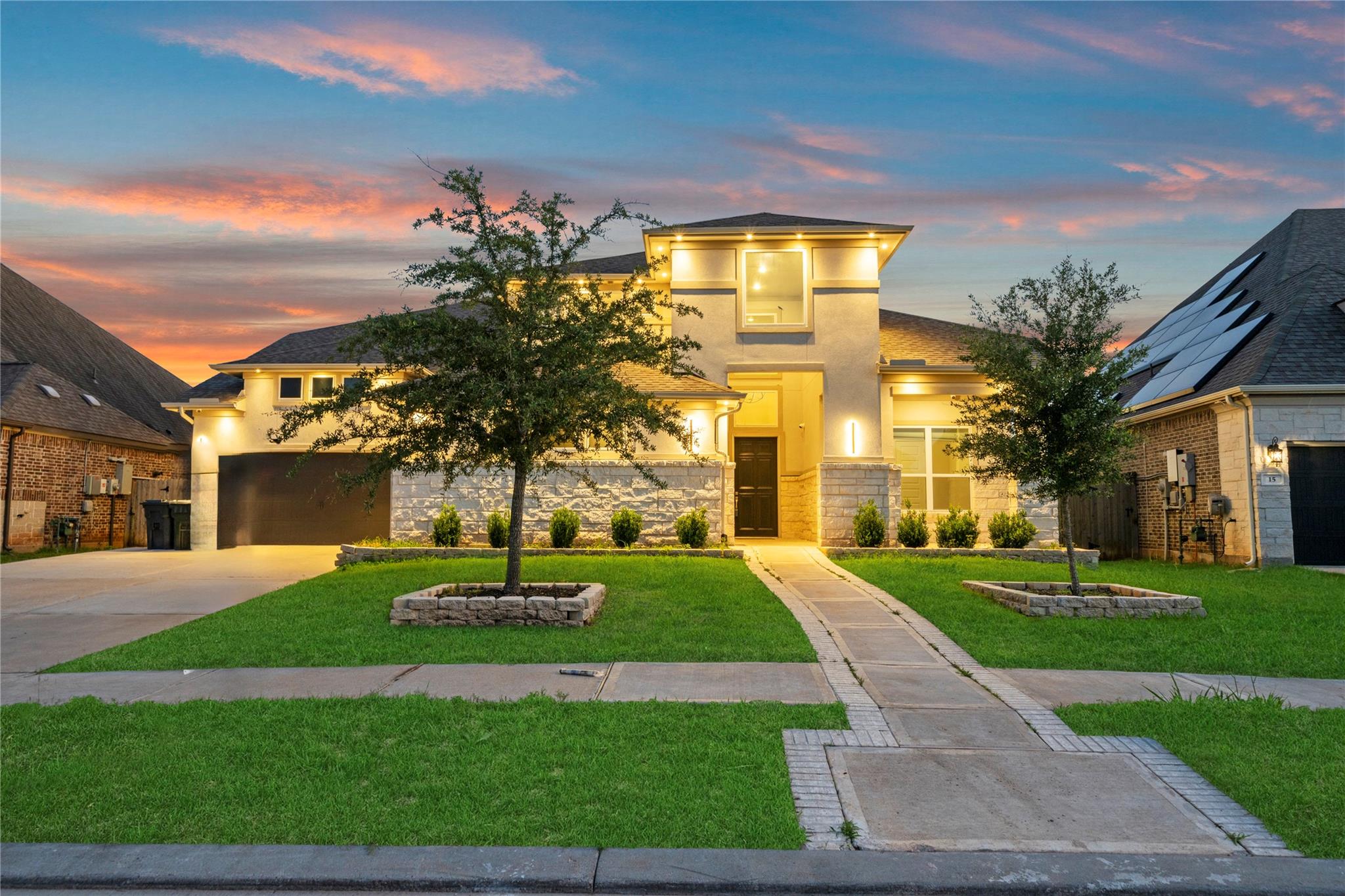 Modern two-story home with a stone-accented facade and curved front walkway at dusk