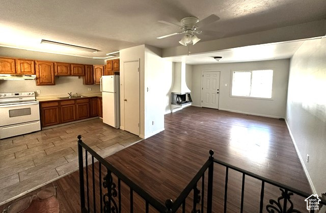 Open-plan kitchen and living area with wood cabinets, dark floors, and a corner fireplace.