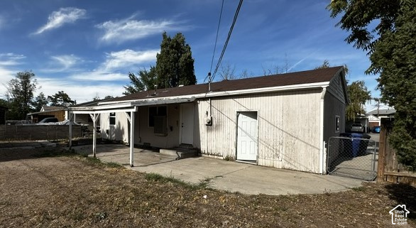 Single-story home's rear exterior with covered patio, concrete walkway, and fenced dry yard.