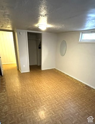 Vacant room with parquet flooring, a closet opening, and a small high window.