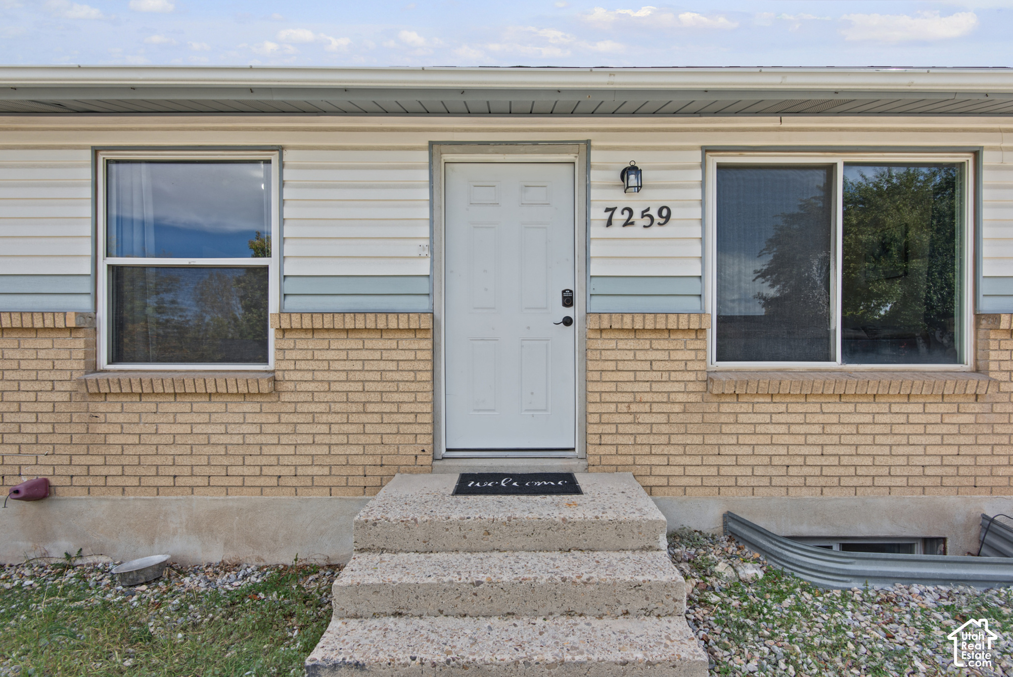 Home entrance with a white door marked 7259, flanked by windows above tan brick.