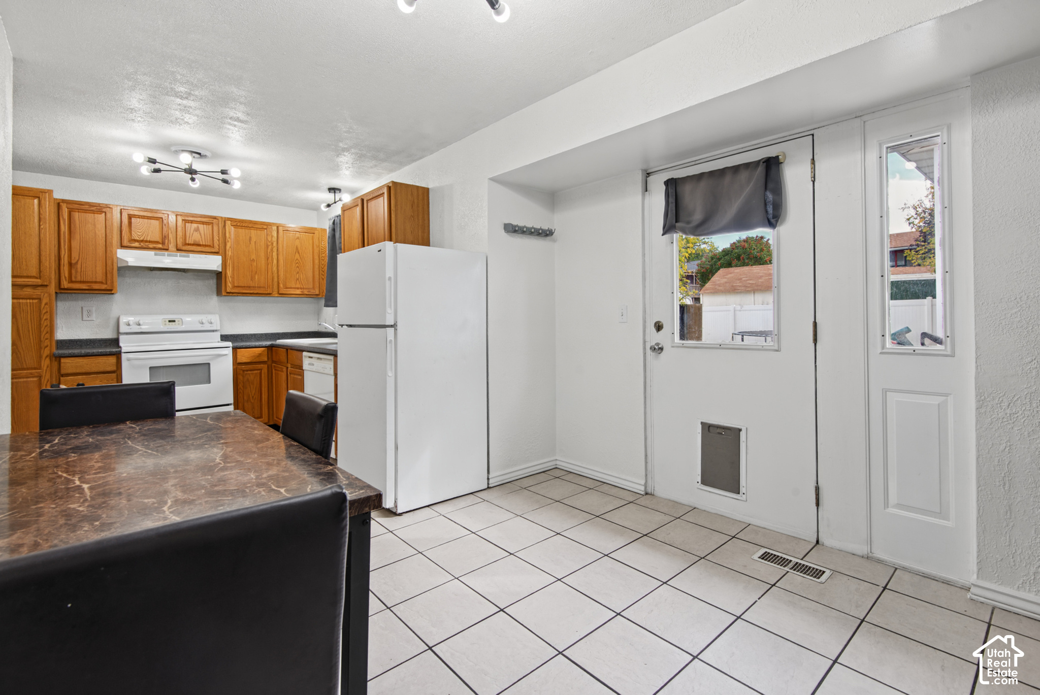 Kitchen and dining area with wood cabinets, white appliances, and a dark marbled table.