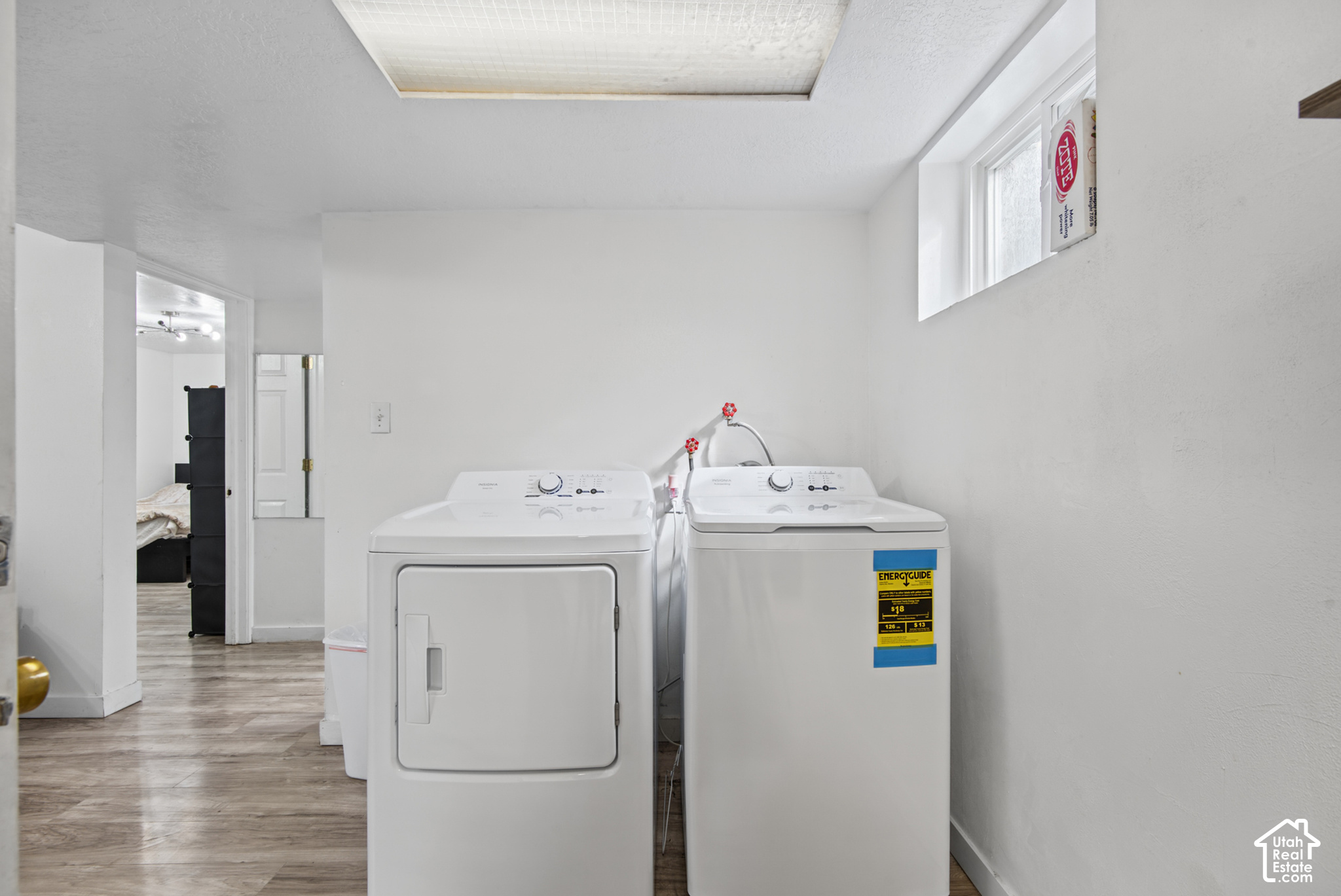 Laundry room with a white dryer and top-loading washer beneath a small high window.