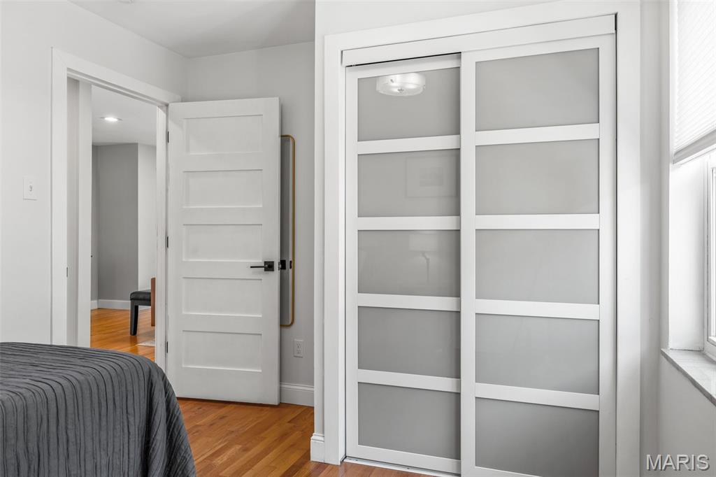 Bedroom with gray bedding, hardwood floors, and large sliding closet doors.