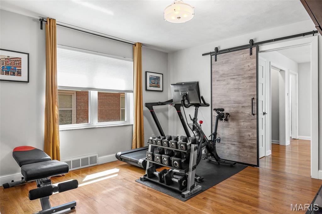 Home gym with treadmill, stationary bike, dumbbells, and weight bench on hardwood floors.