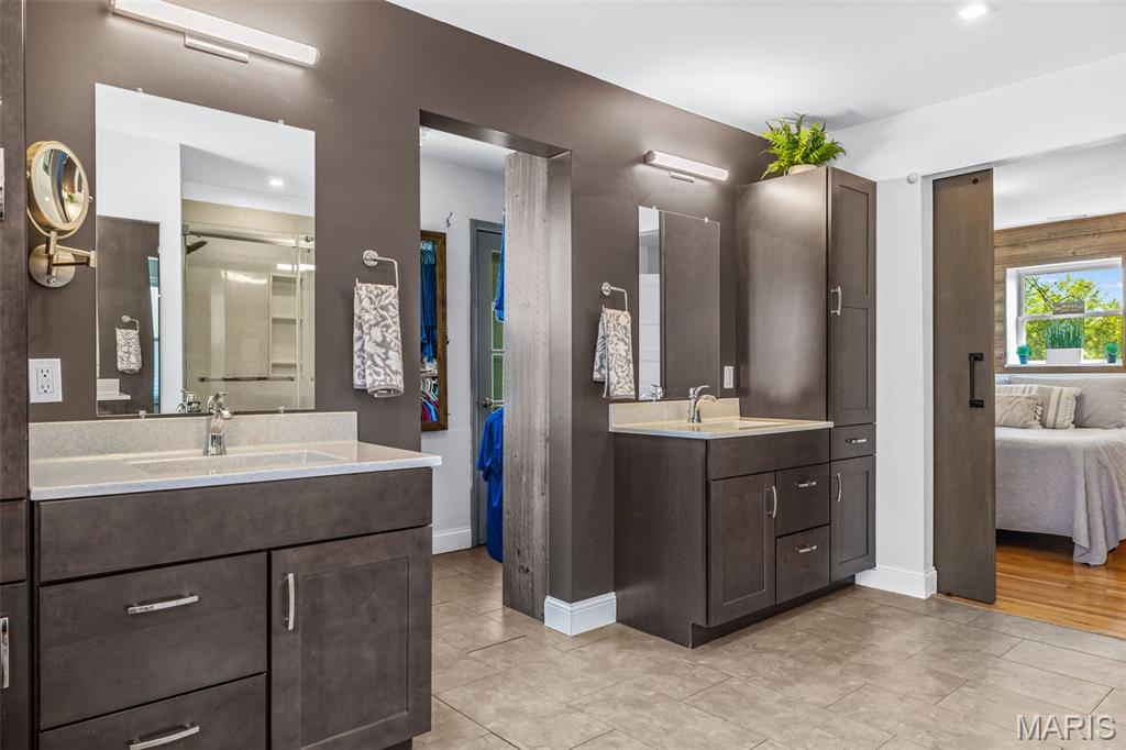 Bathroom with two dark wood vanities and an open doorway to a bedroom.