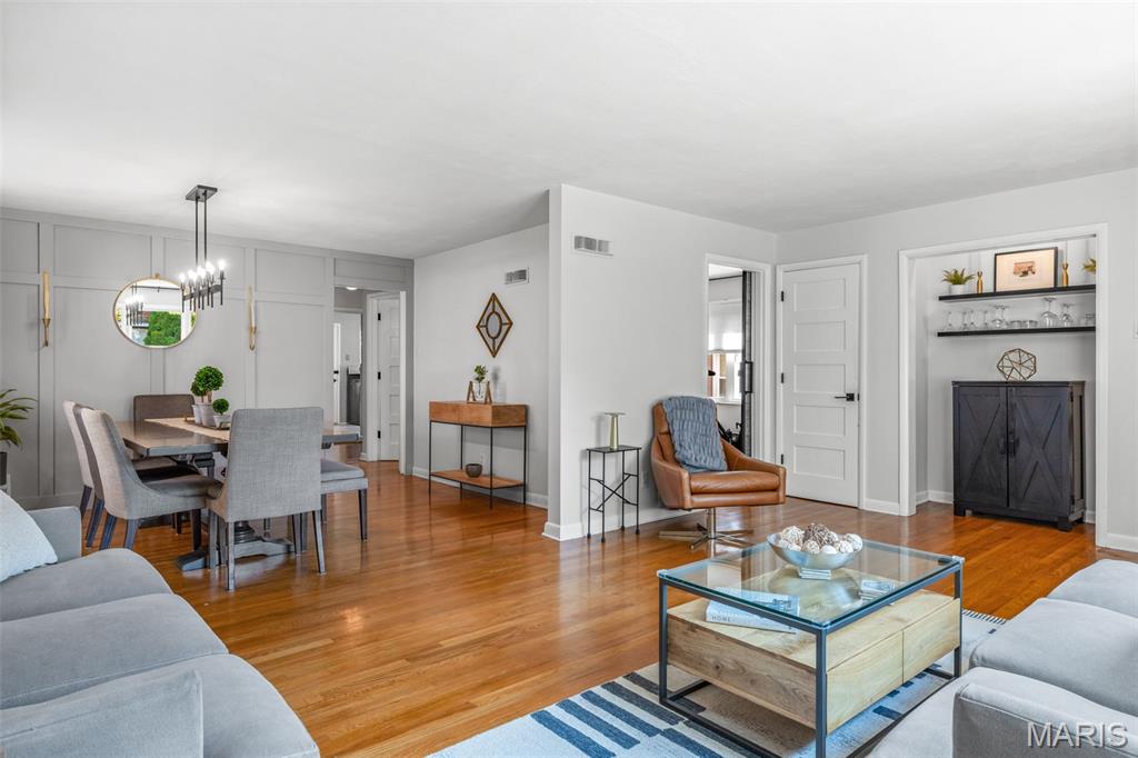 Open-plan living and dining room with hardwood floors, gray seating, and built-in shelving.
