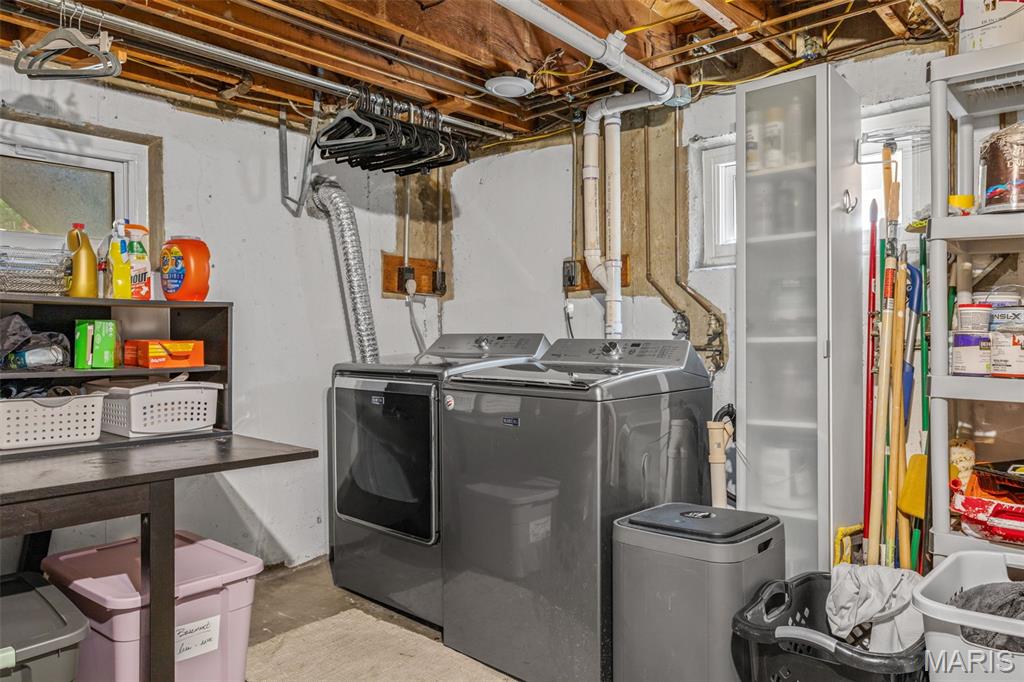 Basement laundry area with a washer, dryer, utility sink, and storage shelves.