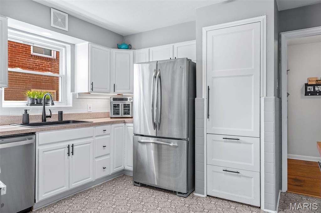 Kitchen with white shaker cabinets, stainless appliances, and a sink beneath a window.