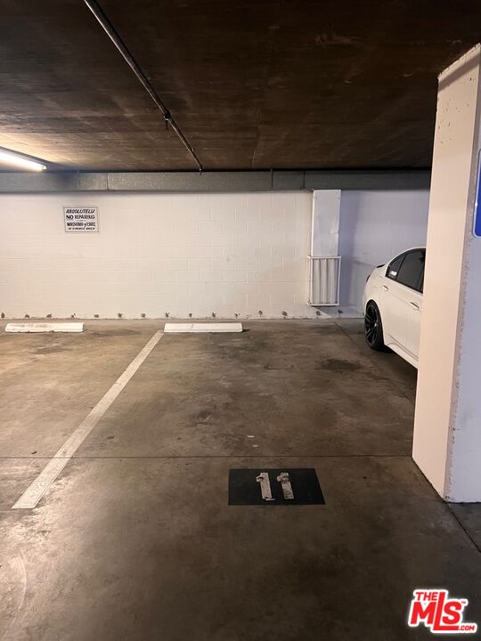 Indoor parking garage with marked space 11 beside a partially visible white car.