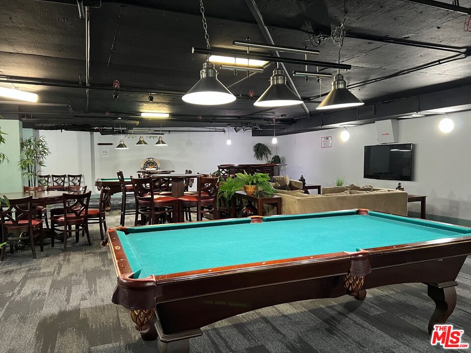 Recreation room with a turquoise pool table, dining tables, and a sofa seating area.