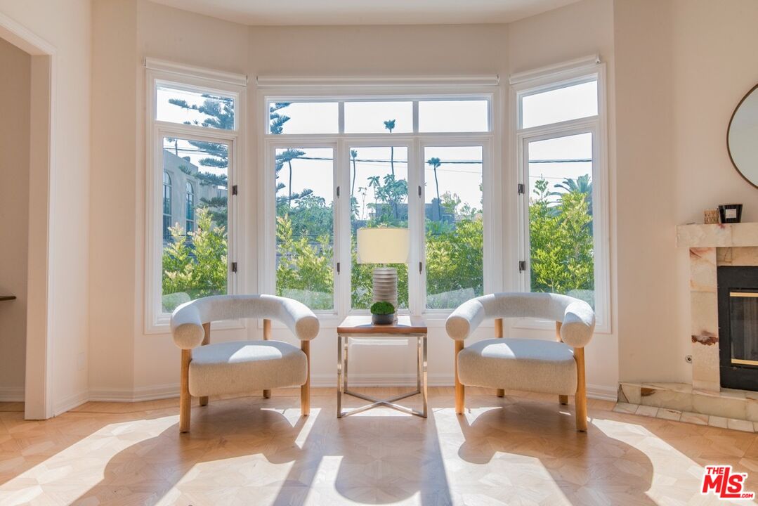 Living room with two chairs before large windows and a stone fireplace.
