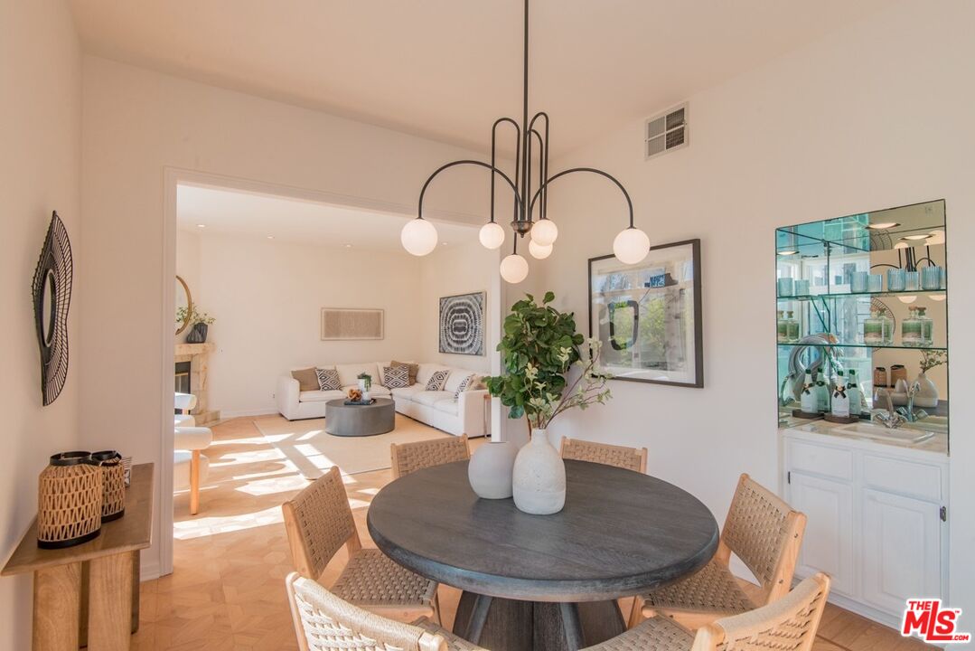 Dining area with round table and woven chairs opening to a bright living room with a white sectional.