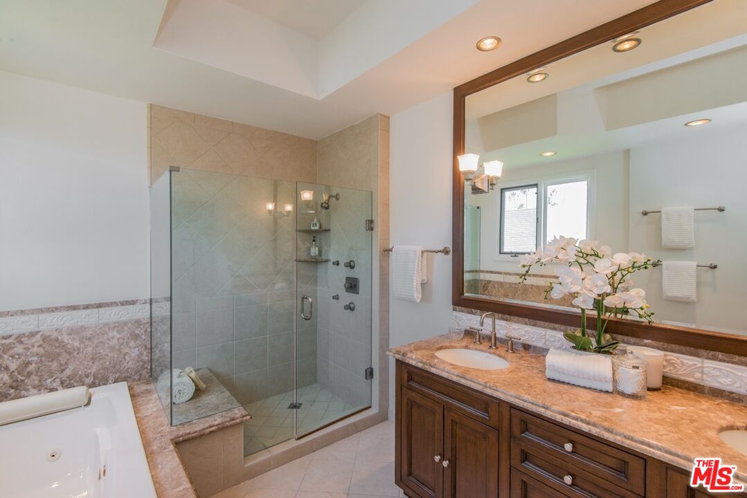 Bathroom with a glass-enclosed shower, soaking tub, and marble-topped dark wood vanity.