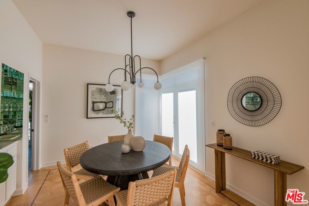 Dining room with a round table, woven chairs, pendant light, and bright glass doors.