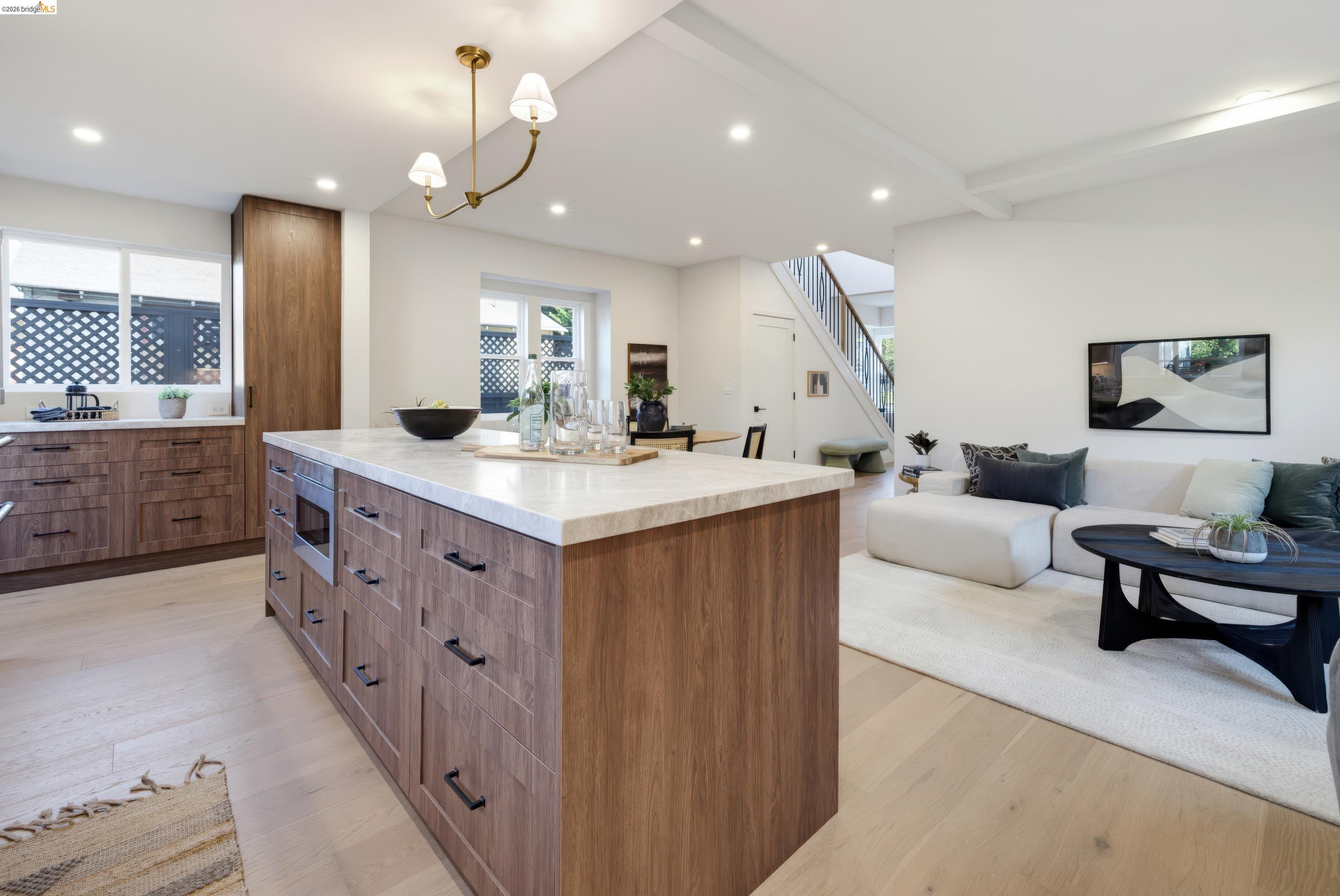 Open-plan kitchen with a large wood island and white countertop beside a bright living room.