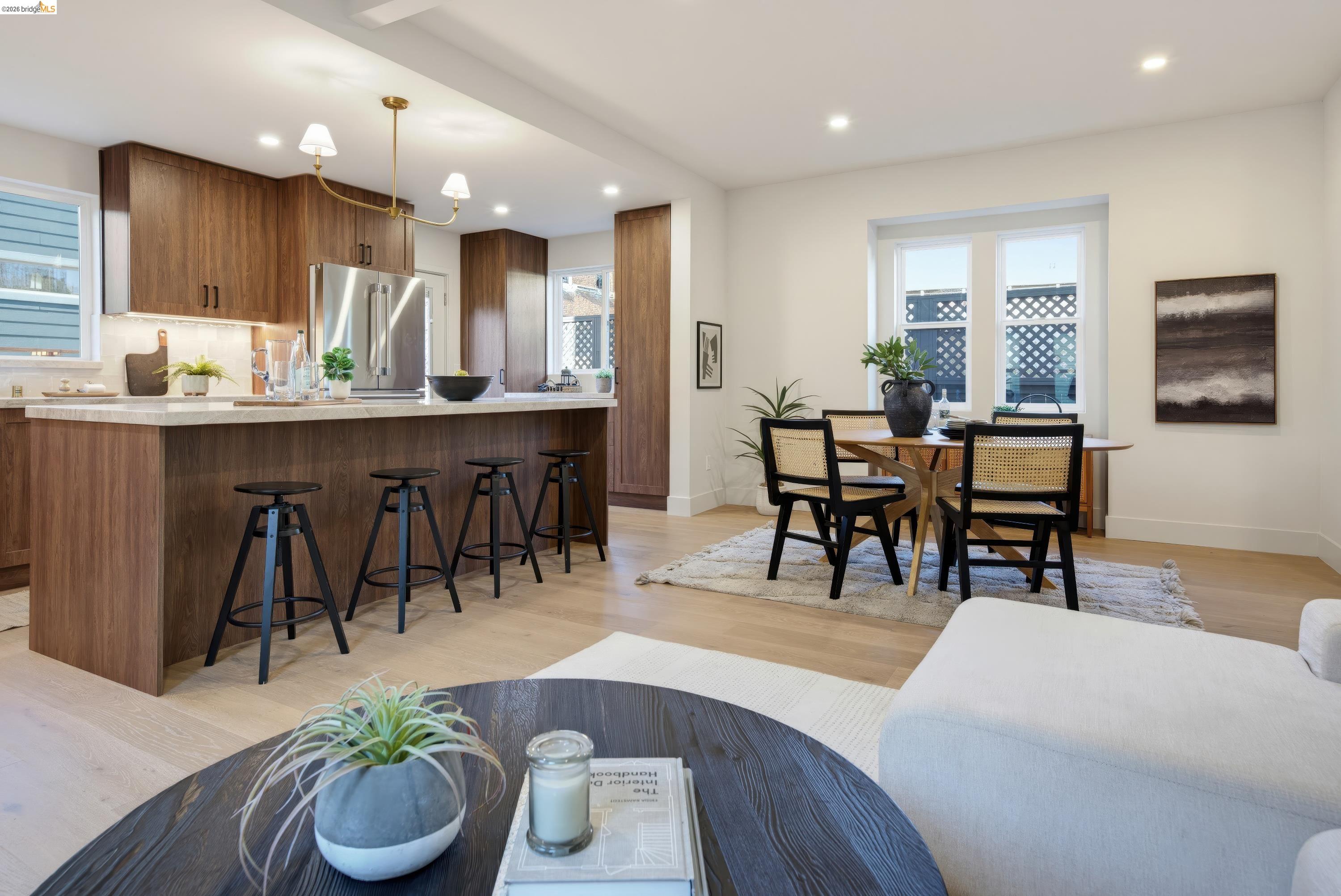 Open-plan kitchen and dining area with dark wood cabinetry, island seating, and a table beside two windows.