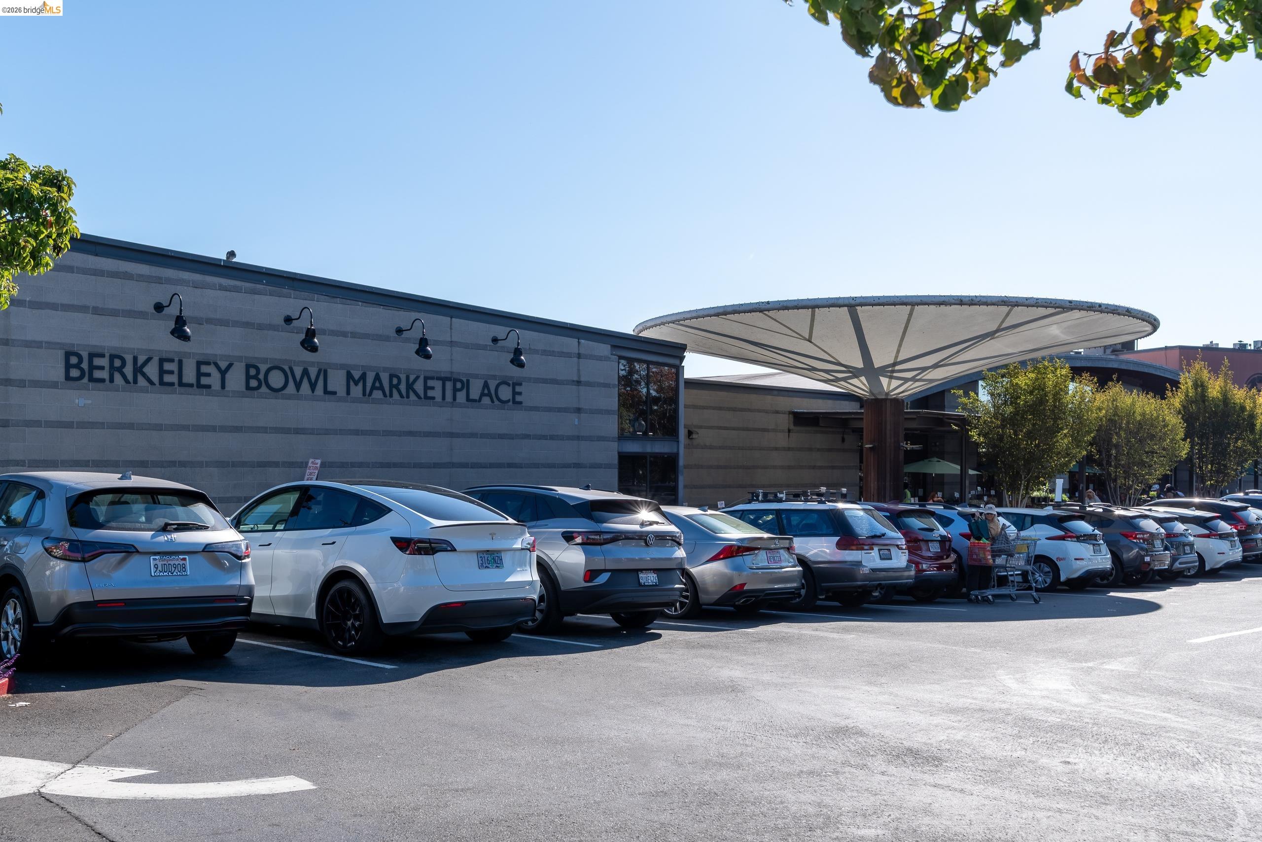 Berkeley Bowl Marketplace with its wide circular canopy and parked cars in front.