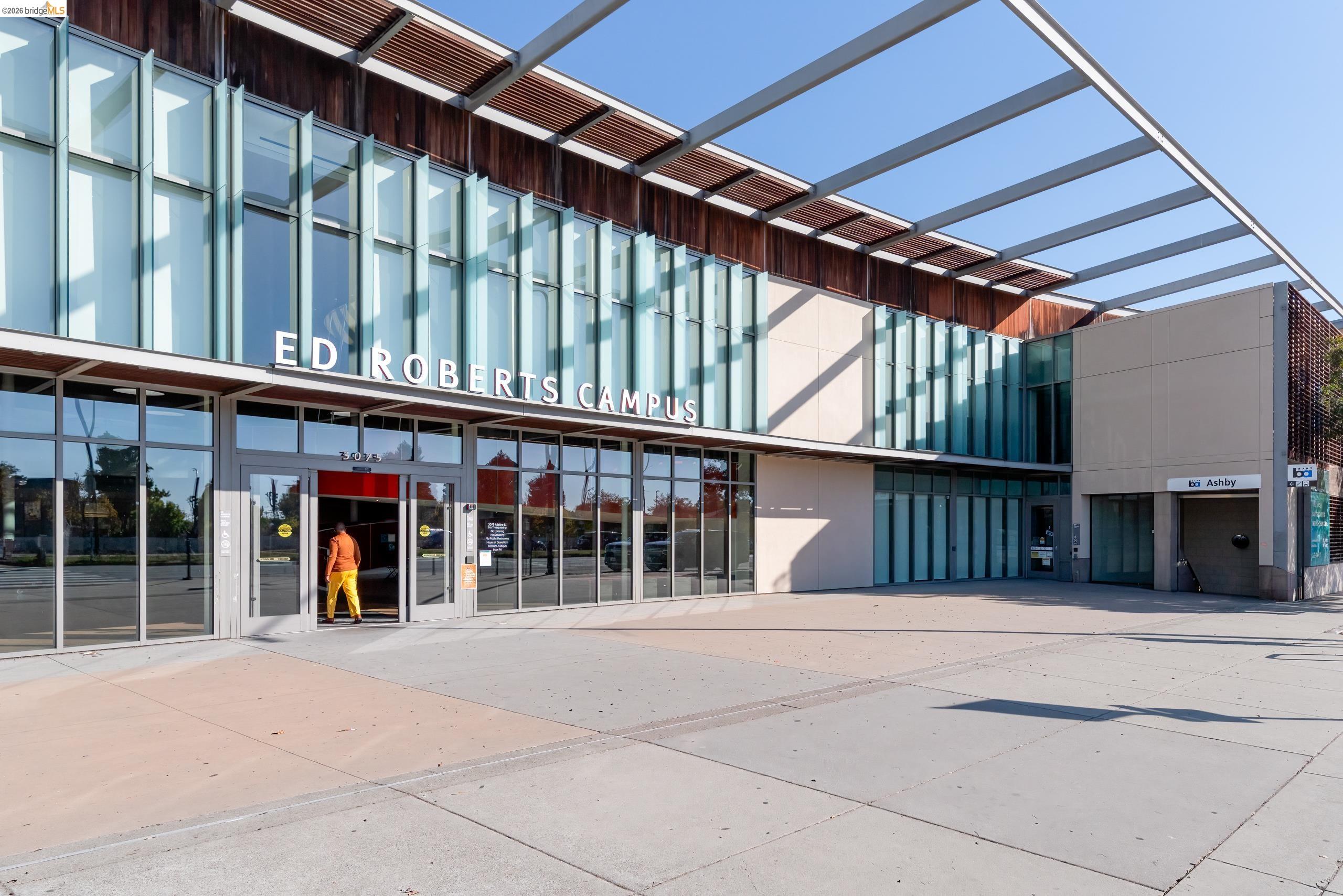Ed Roberts Campus exterior with a glass facade and broad canopy beside the Ashby BART entrance.