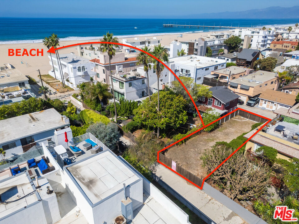Aerial view of a vacant coastal lot outlined in red, near the beach and ocean.