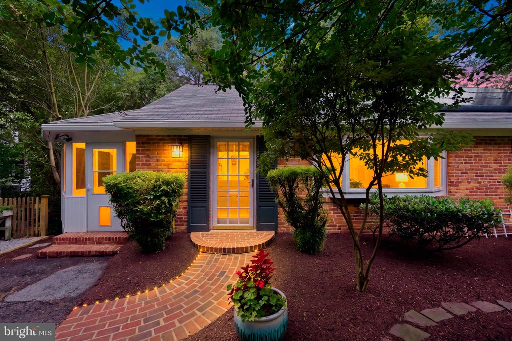 Brick home at dusk with glowing windows and a curved brick walkway to the front door.