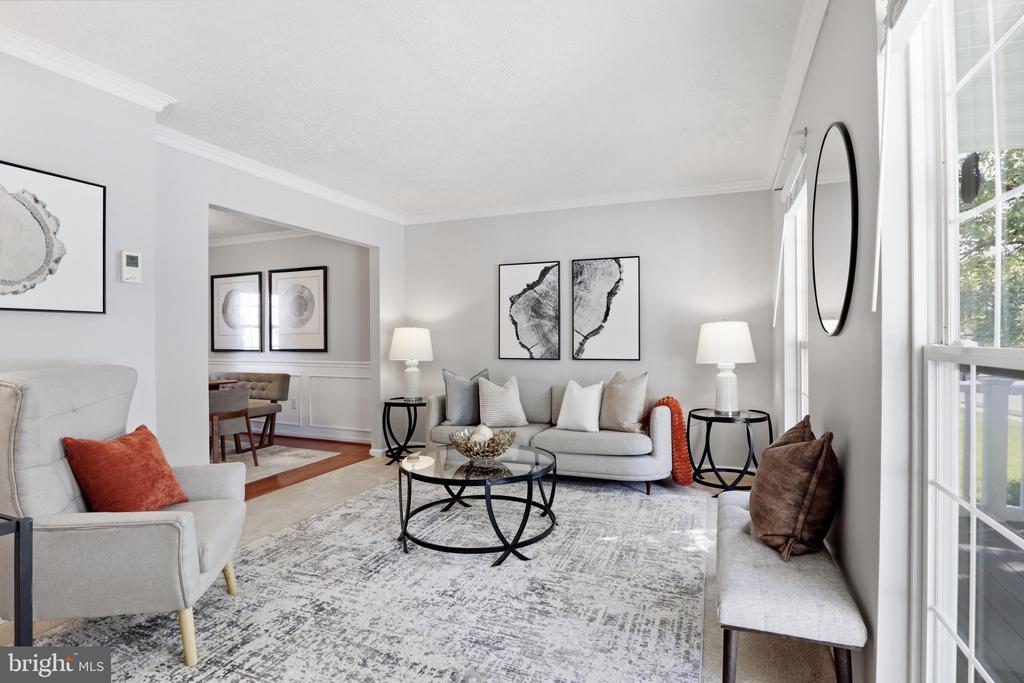 Staged living room with gray seating, a round glass coffee table, and large windows.