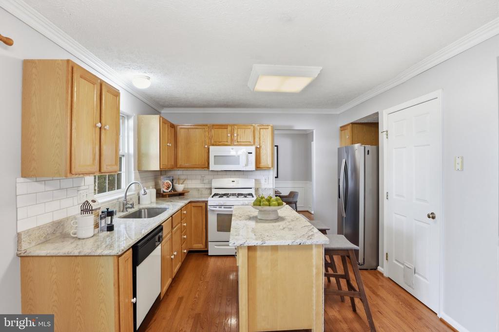 Kitchen with wood cabinets, granite island, subway tile backsplash, and stainless steel refrigerator.