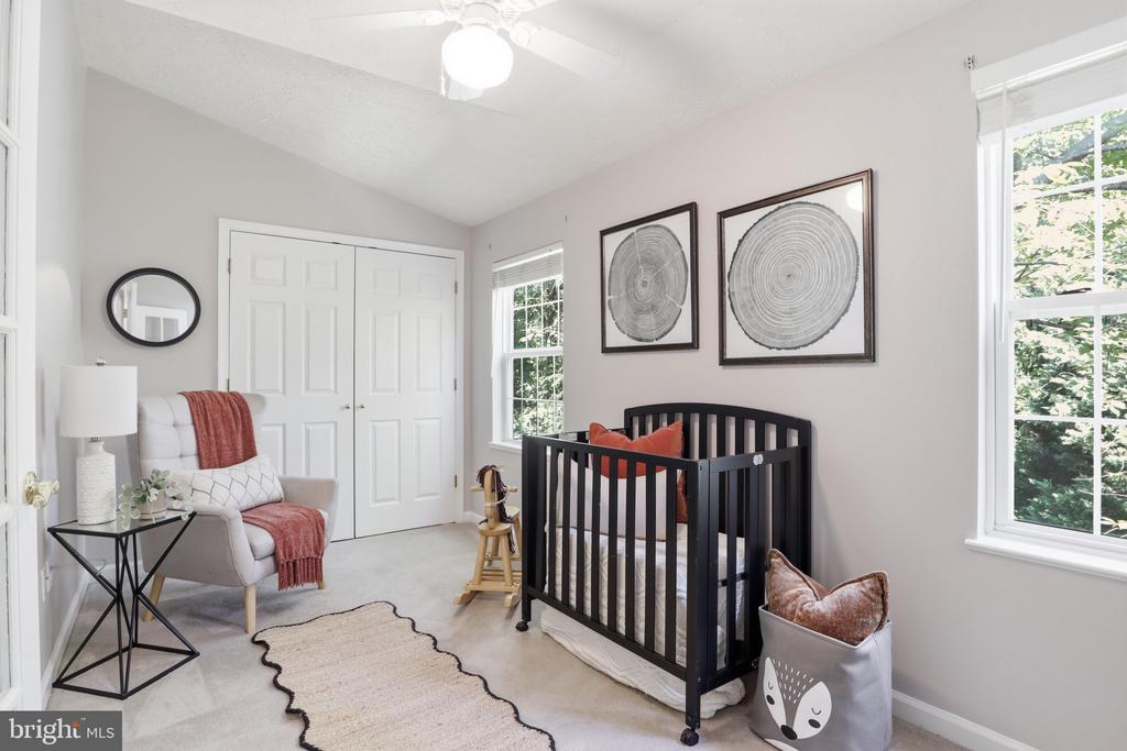 Staged nursery with a black crib, coral accents, and large windows.