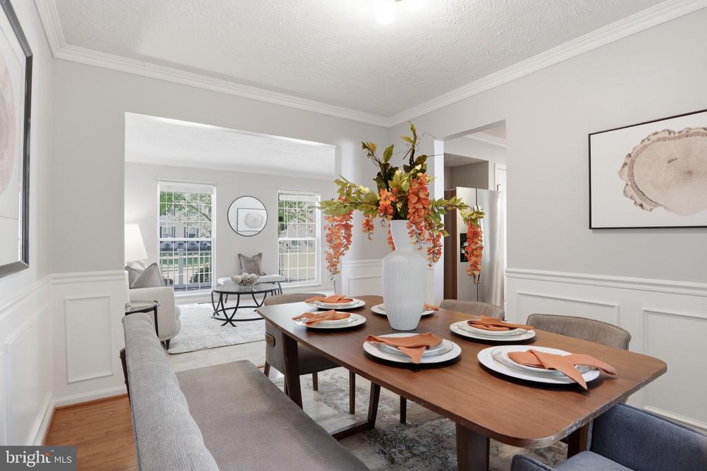 Staged dining room with a set wood table and large windows opening to the living room.