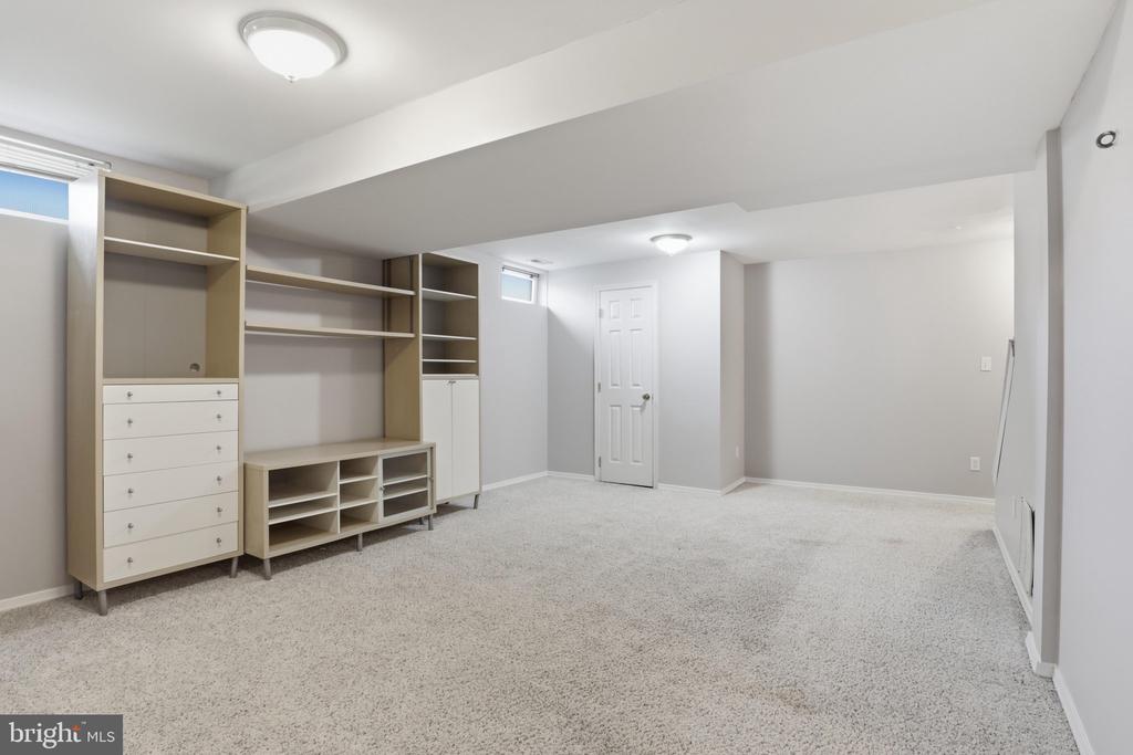 Carpeted basement room with built-in shelving and drawers along one wall.