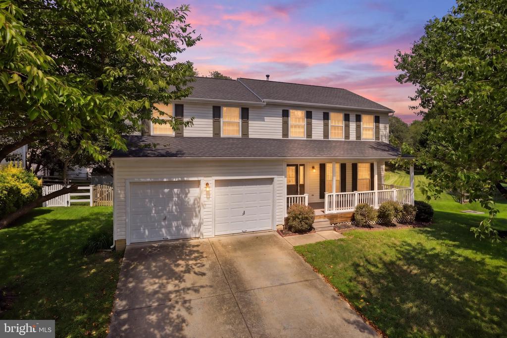 Two-story home with a two-car garage and covered porch at dusk.