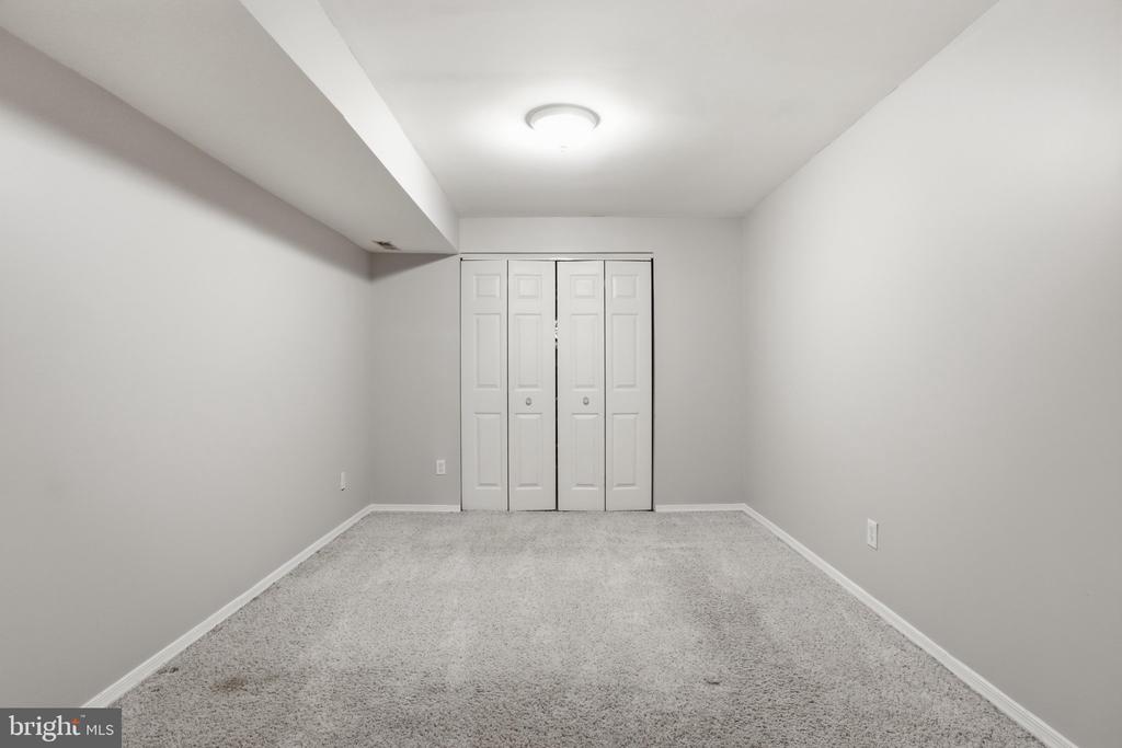 Empty carpeted room with white bifold closet doors and a low ceiling soffit.