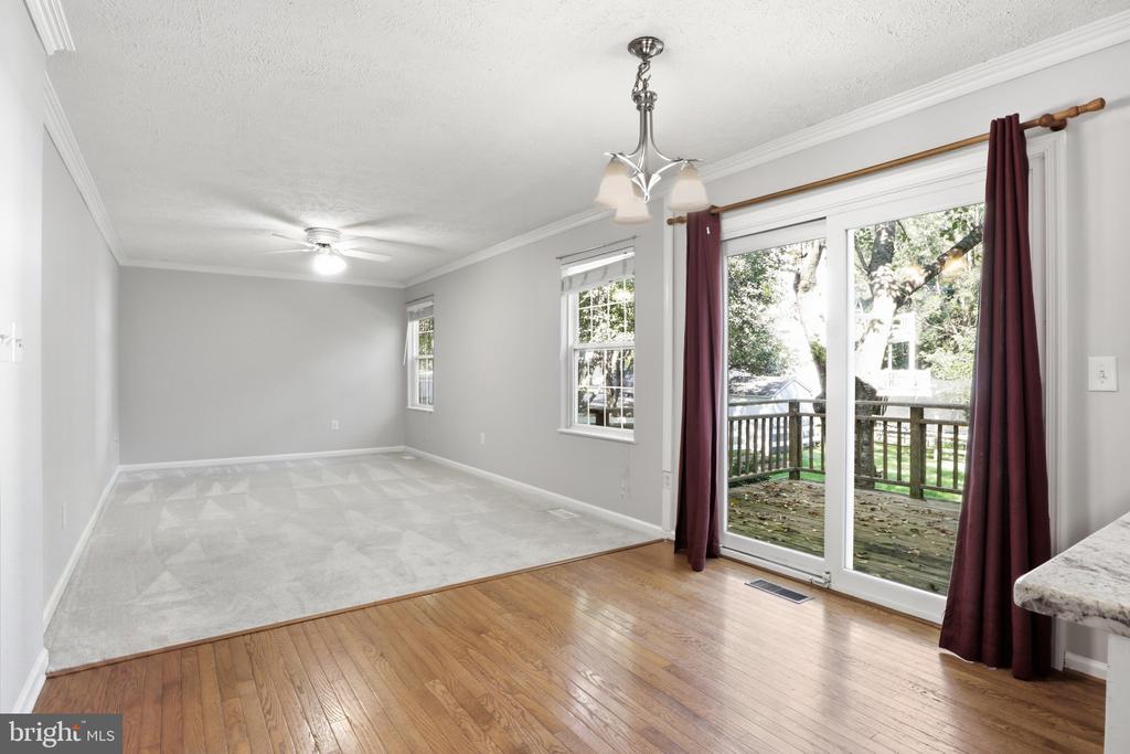 Unfurnished room with hardwood and carpet flooring, burgundy curtains, and sliding doors to a deck.