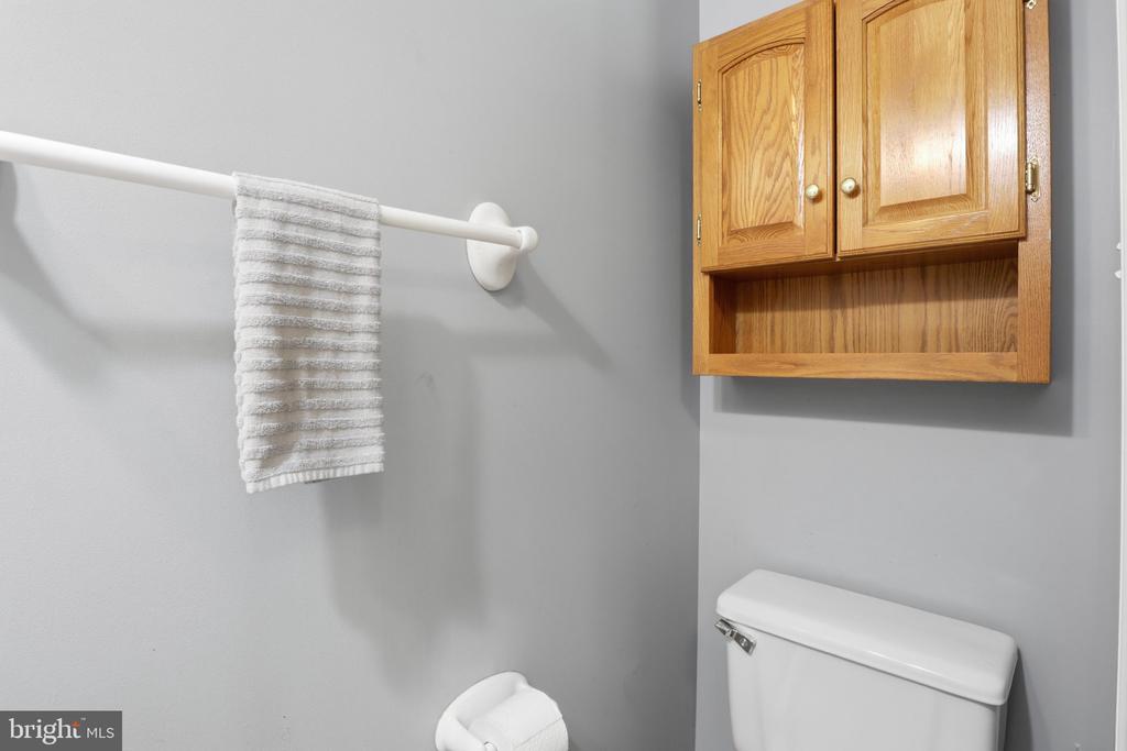 Bathroom with a wooden wall cabinet, white towel, and partial view of the toilet.