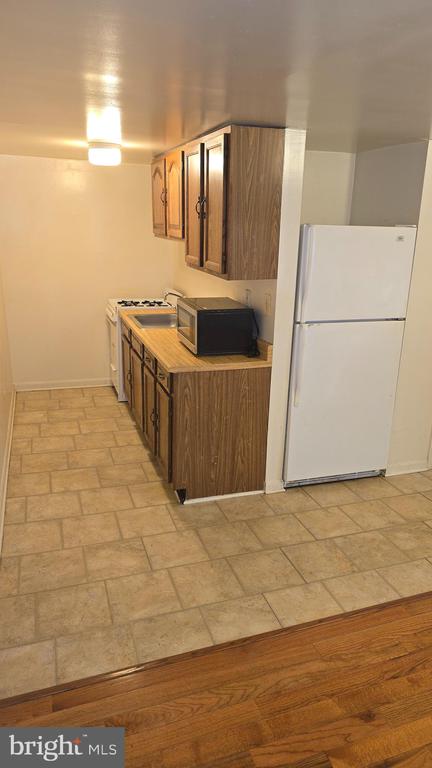 Kitchen with wood-grain cabinets, white refrigerator, stove, and microwave.