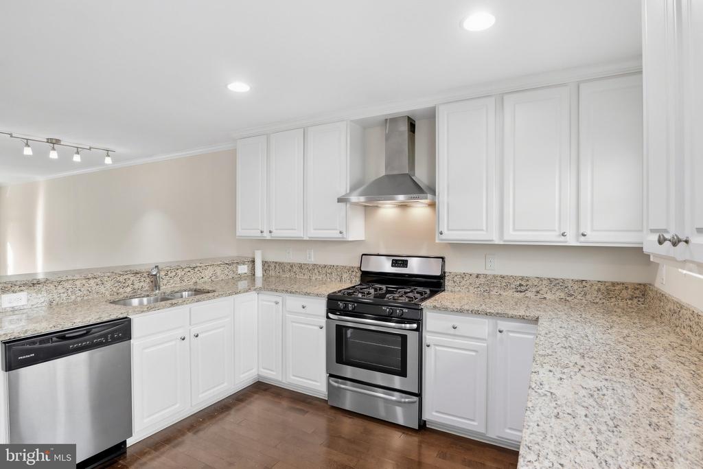 Kitchen with white cabinets, granite counters, and a stainless-steel gas range.