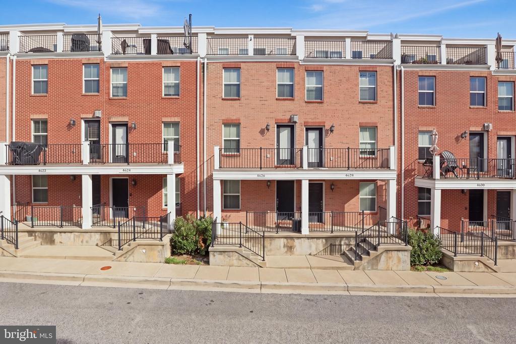 Red-brick townhome at 4626 Dillon Place with black-railed balconies and front steps.