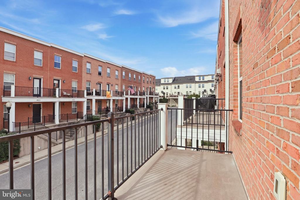 Brick balcony overlooking a courtyard between red-brick townhomes.