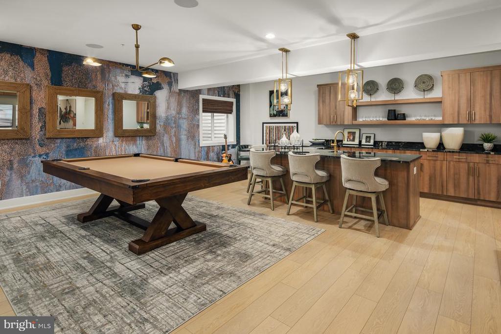 Game room with a pool table and wood bar with three stools.